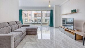 Una sala moderna con un sofá seccional gris, un televisor de pantalla plana y una mesa de centro de madera.