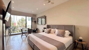 Ein modernes Hotelzimmer mit einem großen Bett, einem Schreibtisch und einem Balkon mit Blick auf die Stadt.