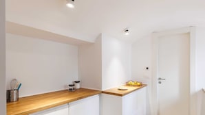 Una cocina moderna con armarios blancos, encimera de madera y una puerta.