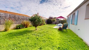 A well-maintained backyard with a lawn, a small tree, and a patio area with outdoor furniture.