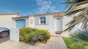Ein zweistöckiges Haus mit einer blauen Tür, einem kleinen Fenster mit Fensterläden und der Hausnummer 22 an der Wand.