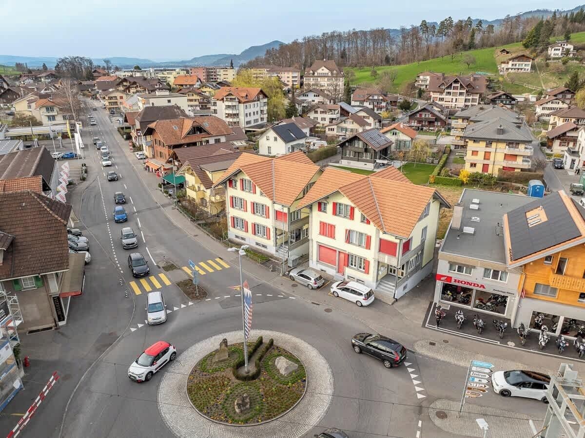A town square with a roundabout, surrounded by residential buildings and a Honda dealership.