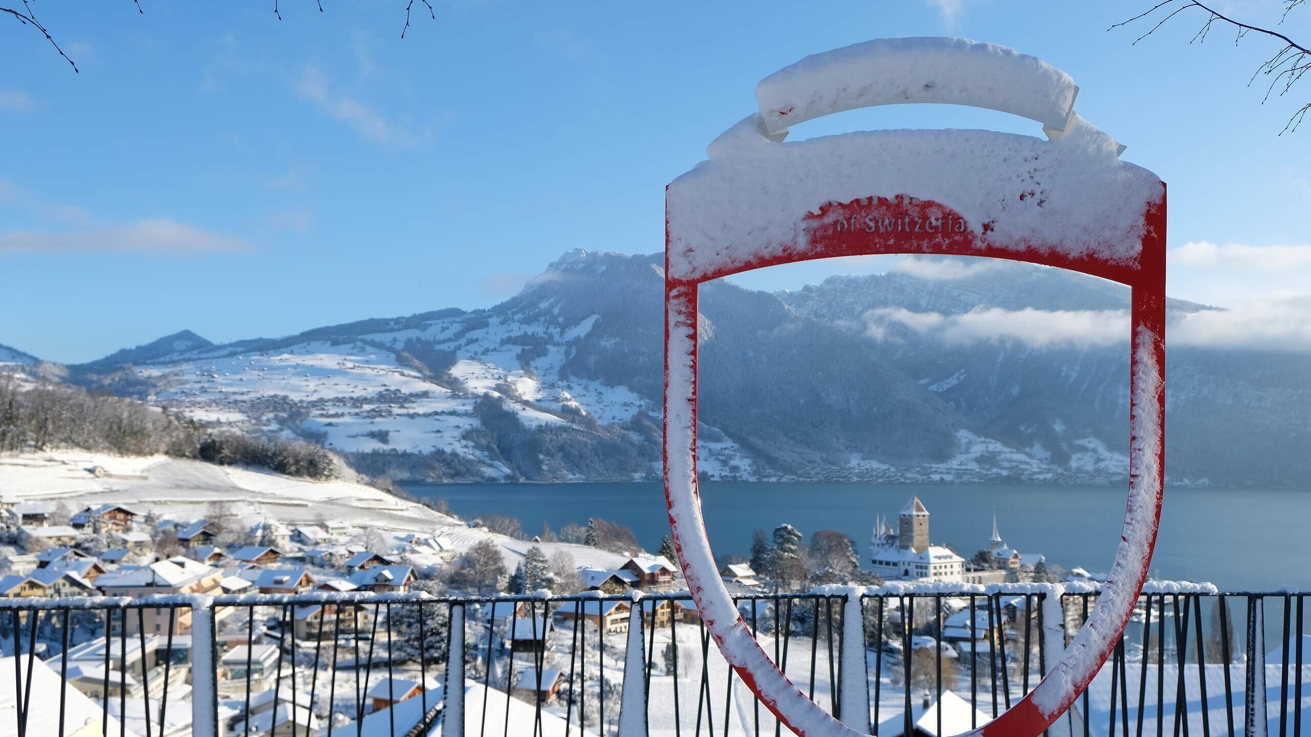 Un paysage montagneux enneigé, avec un lac et un village en arrière-plan.
