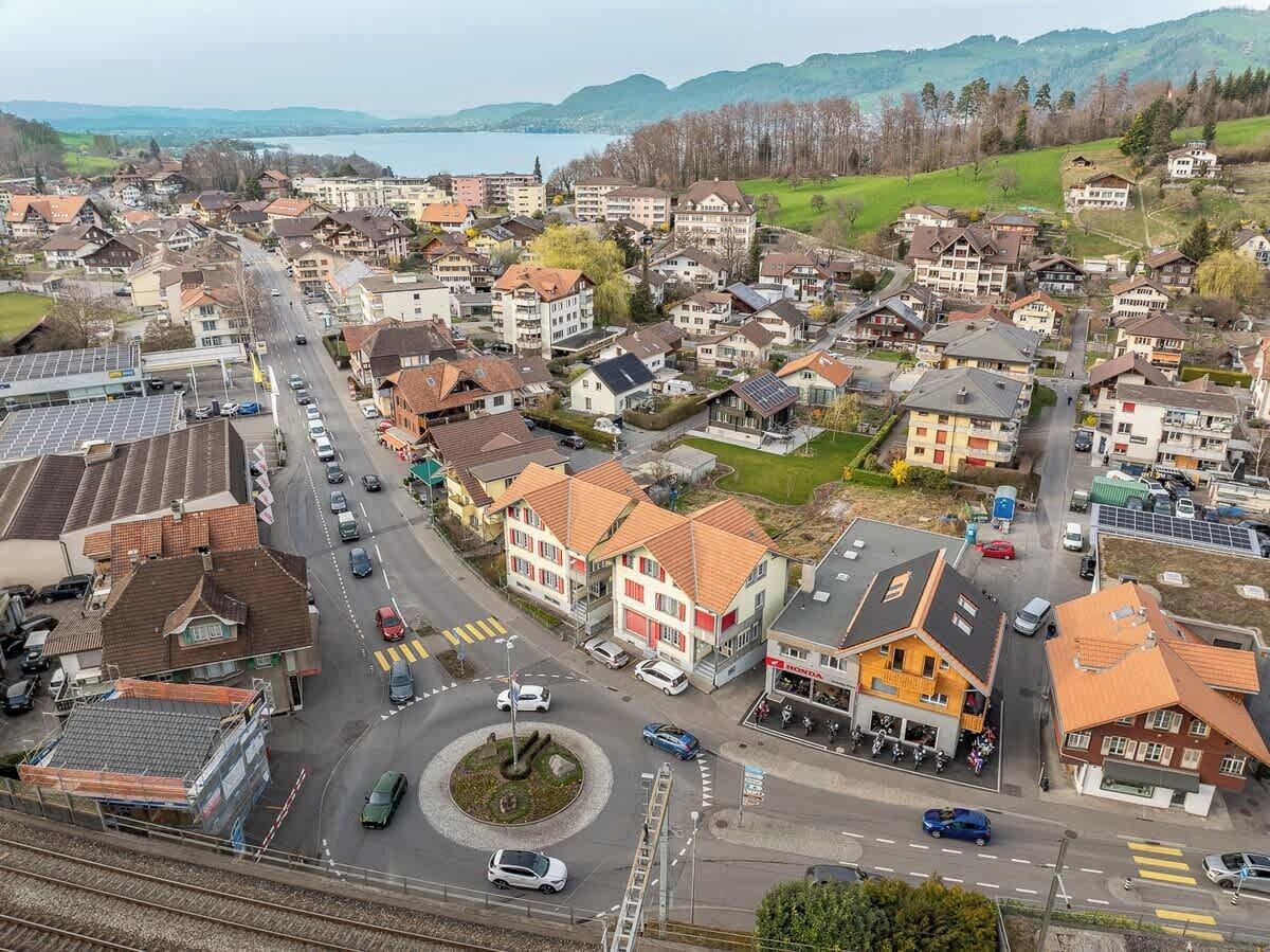 A residential area with a roundabout, houses, and a body of water in the background.