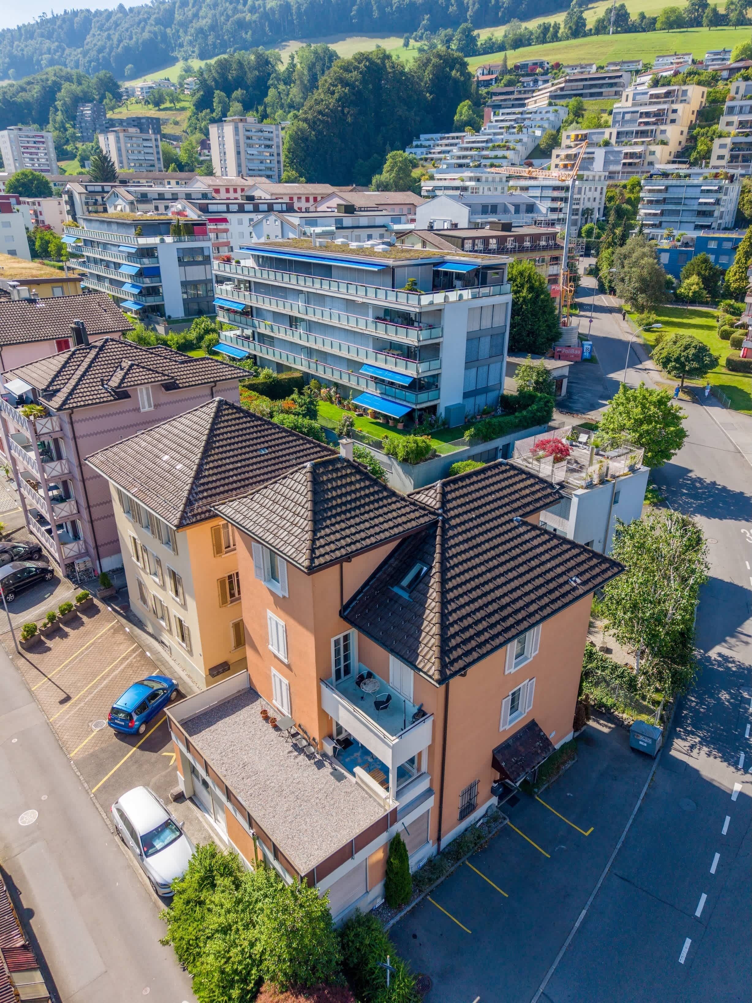 Un immeuble résidentiel à plusieurs étages, doté de balcons, d’un parking et entouré d’un espace vert.