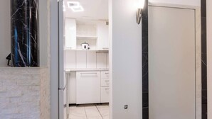 Una cocina moderna con armarios blancos, un pilar de mármol y una puerta con marco negro.