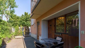 Un patio con mesa y sillas, una puerta de madera y un ventanal con vistas a árboles.