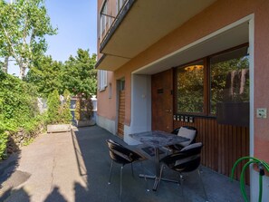 Un patio con mesa y sillas, una puerta de madera y un ventanal con vistas a árboles.