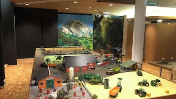 A detailed scale model of a farm with various buildings, vehicles, and a mountainous backdrop.