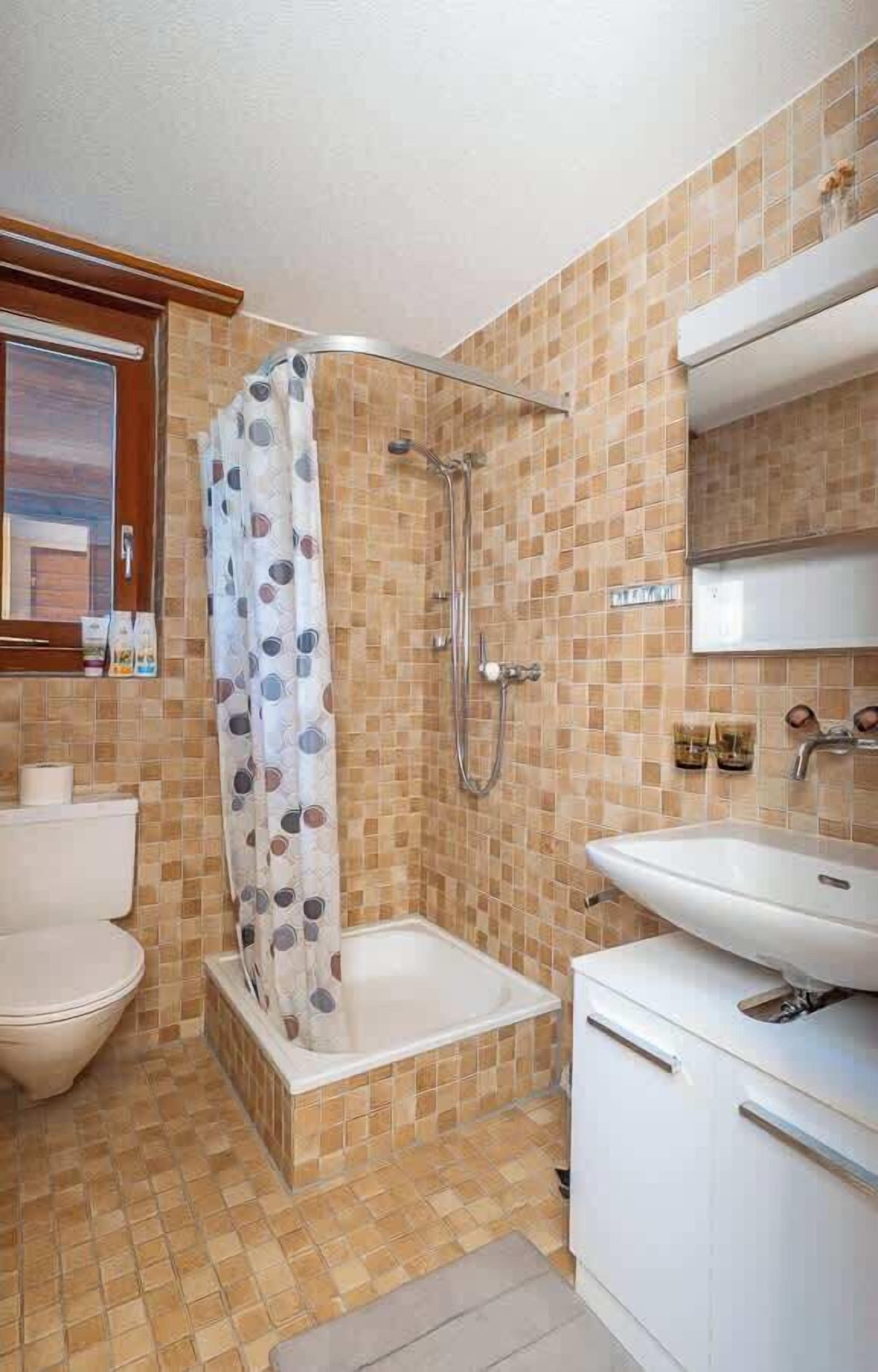 A bathroom with a shower, toilet, and sink.