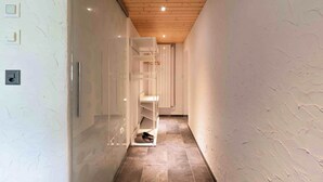 A narrow hallway with a wooden ceiling, white walls, and a tiled floor. - With Hot Tub, Sauna, Garden|with View near Gondola (Diemtigen)