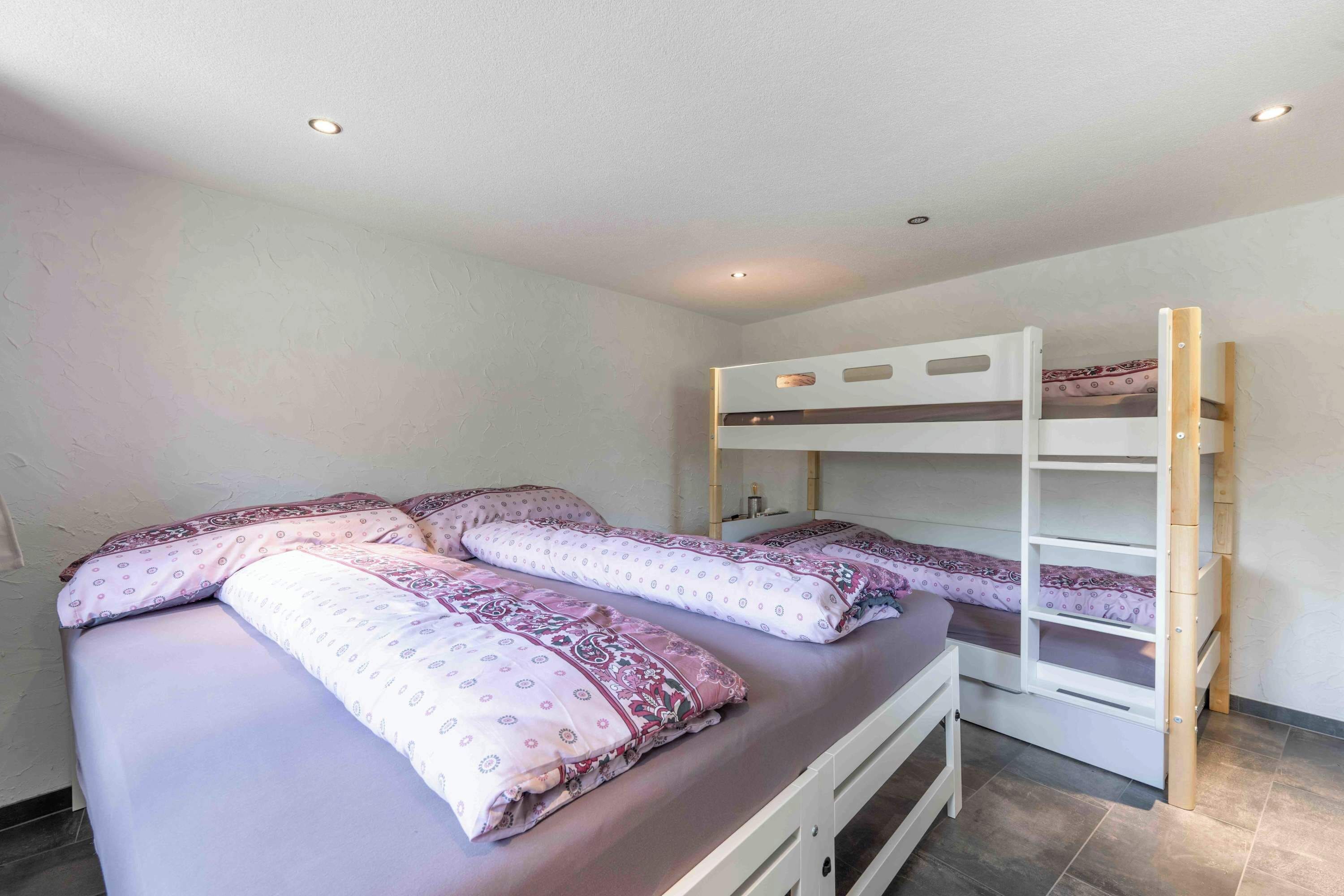 Un dormitorio con literas y una cama individual, todo con ropa de cama estampada.
