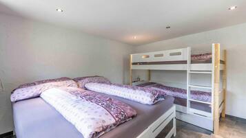 Un dormitorio con literas y una cama individual, todo con ropa de cama estampada.
