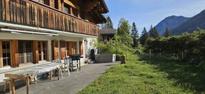 A wooden building with a balcony, outdoor seating, and a grill.