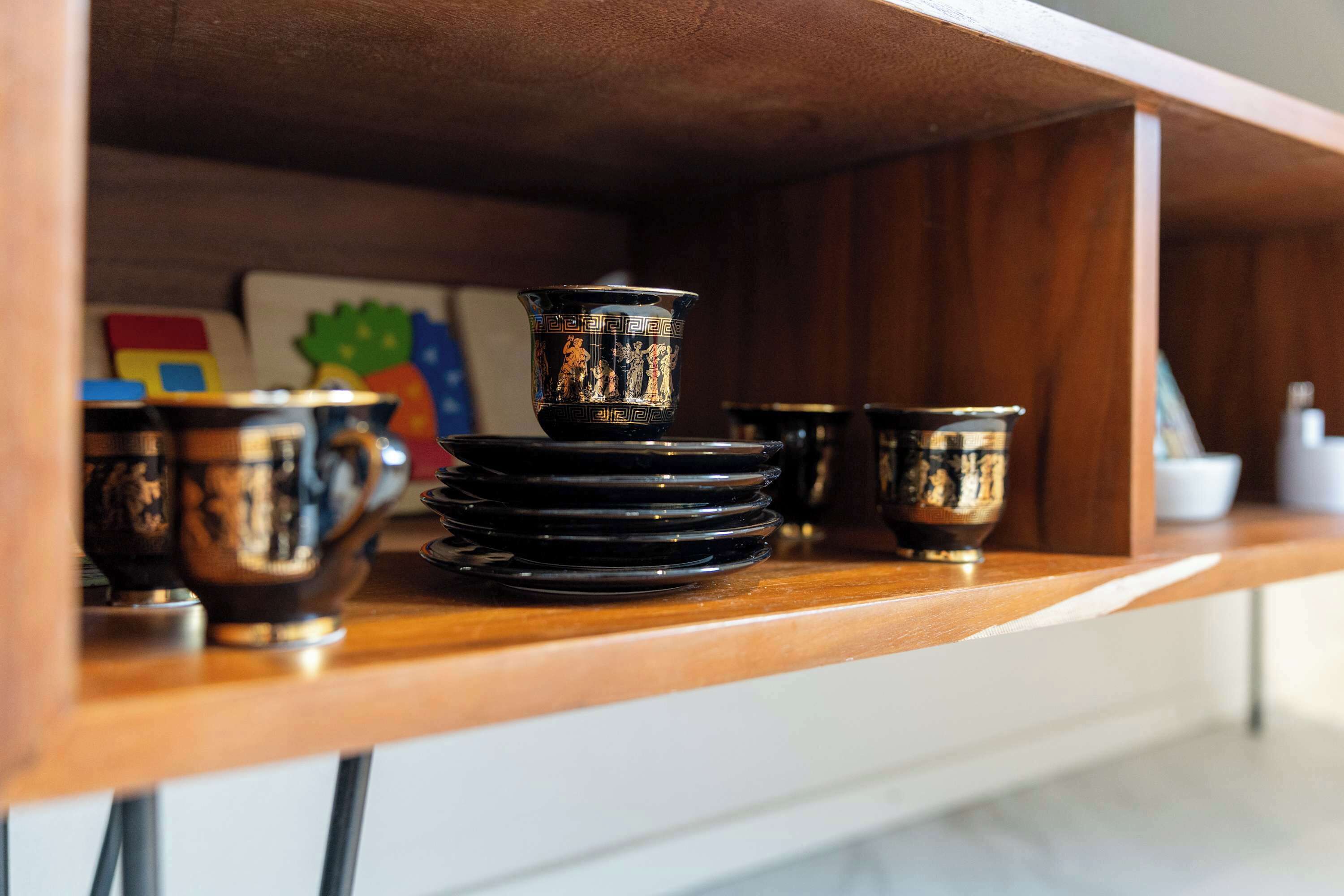 A wooden shelf with black and gold decorative items, including bowls and a small vase.