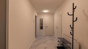 Un couloir étroit doté d’un sol en marbre, d’un porte-manteau et d’un radiateur.
