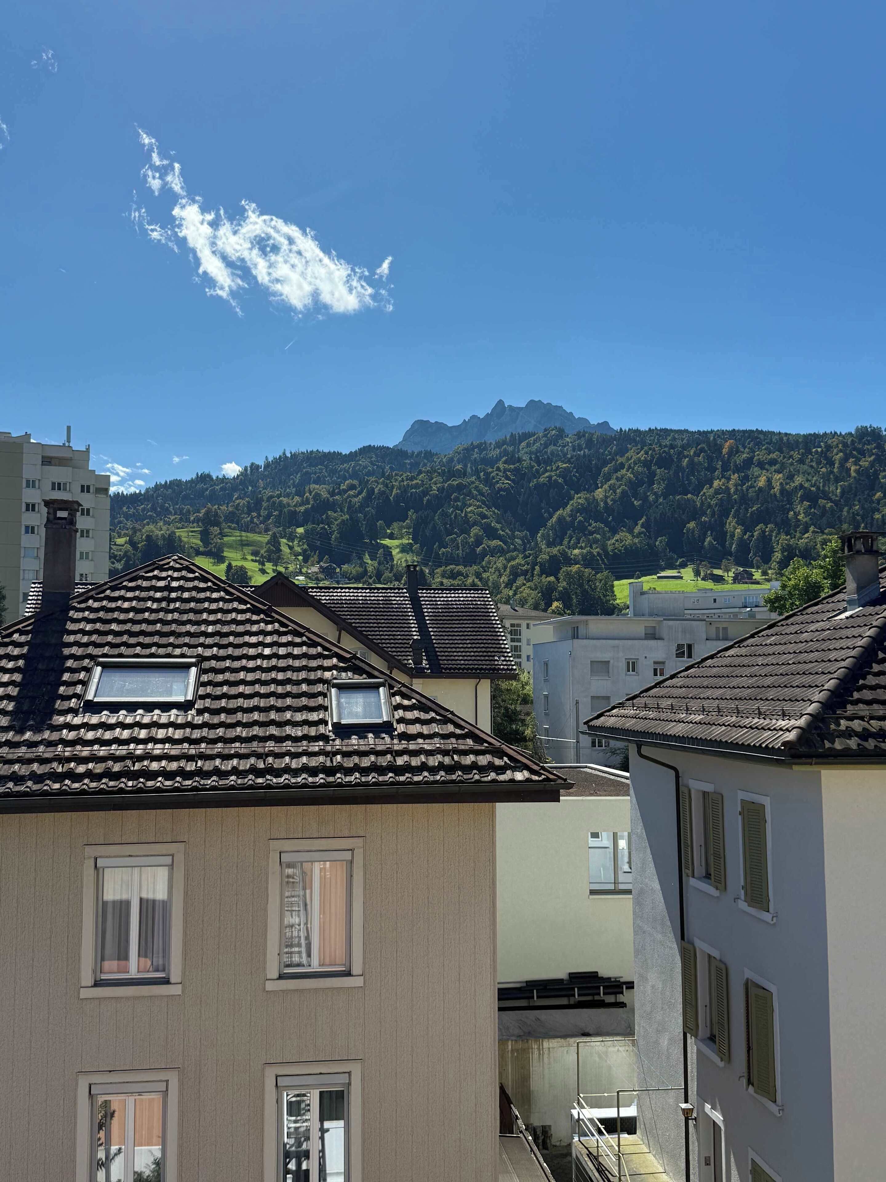 A residential area with terraced houses, a mountain in the background, and a clear sky.