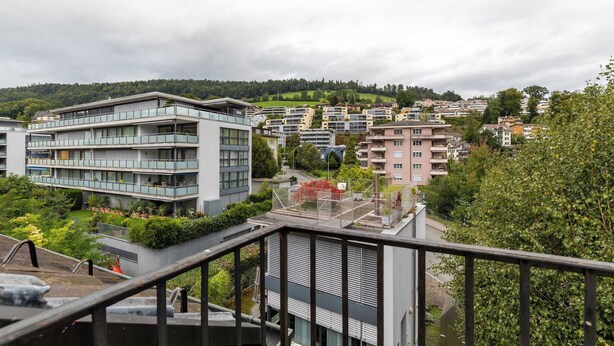 Un bâtiment moderne à plusieurs étages, doté de balcons et entouré de verdure ainsi que d’autres immeubles résidentiels.