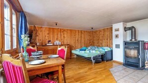Una habitación acogedora con una mesa de comedor de madera, sillas, una cama y una estufa de leña.
