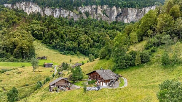 Un pueblo rural con casas de madera tradicionales, un camino sinuoso y un valle boscoso.