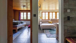 Ein gemütliches Zimmer mit Holzbalkendecke, einer Bank, einem Sofa und einem Teppich.