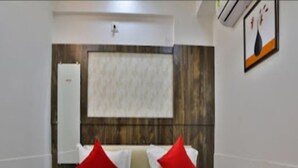 A hotel room with a bed, a wooden headboard, and a wall-mounted air conditioning unit. - Hotel Krishna Palace (Becharaji)