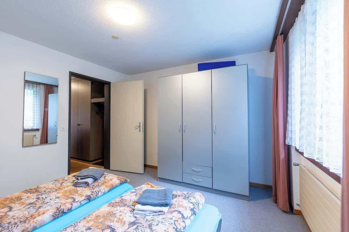 A bedroom with two beds, a wardrobe, and a mirror.