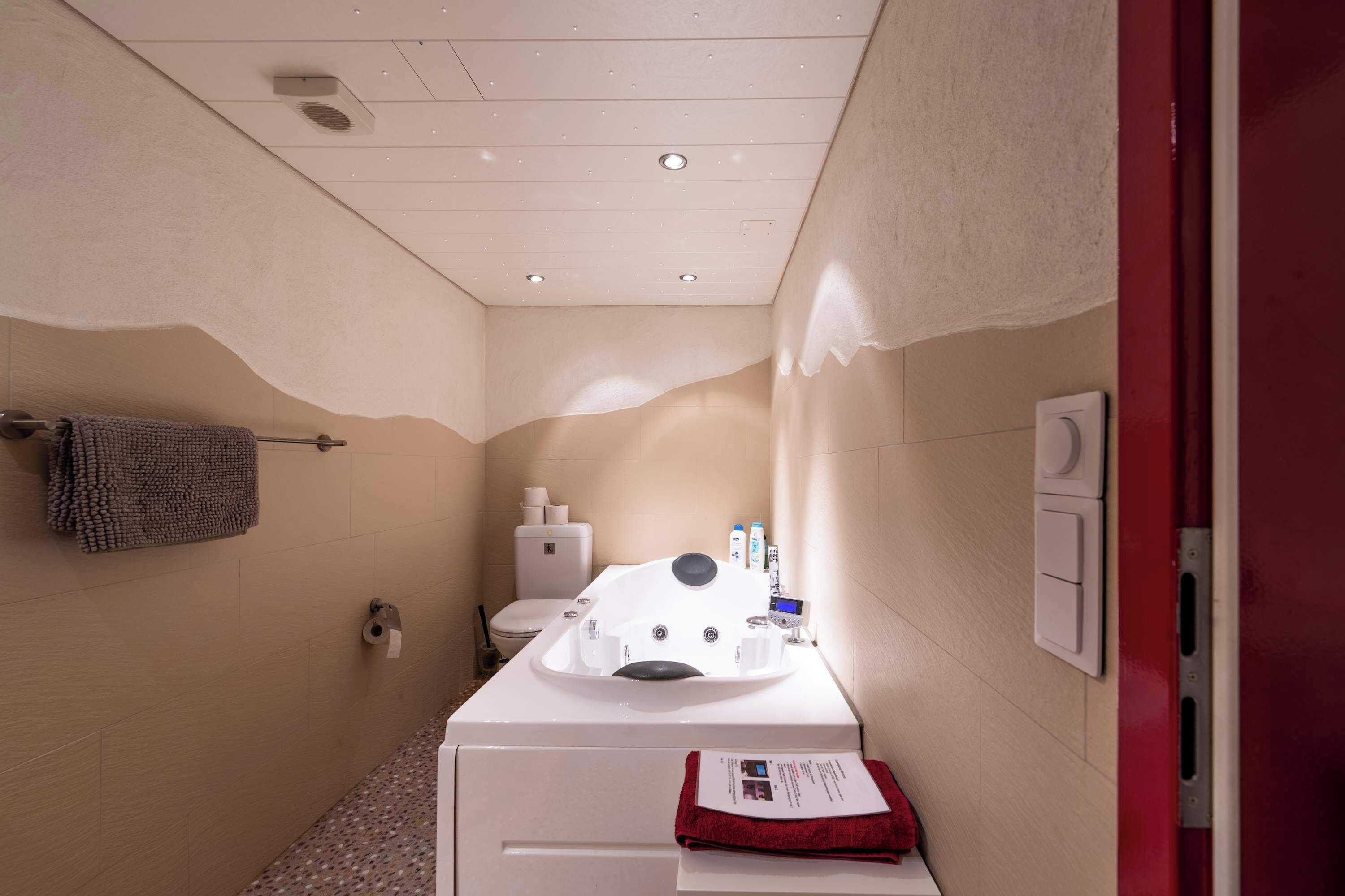 Un baño pequeño con lavamanos blanco, toallero, inodoro y zona de ducha.