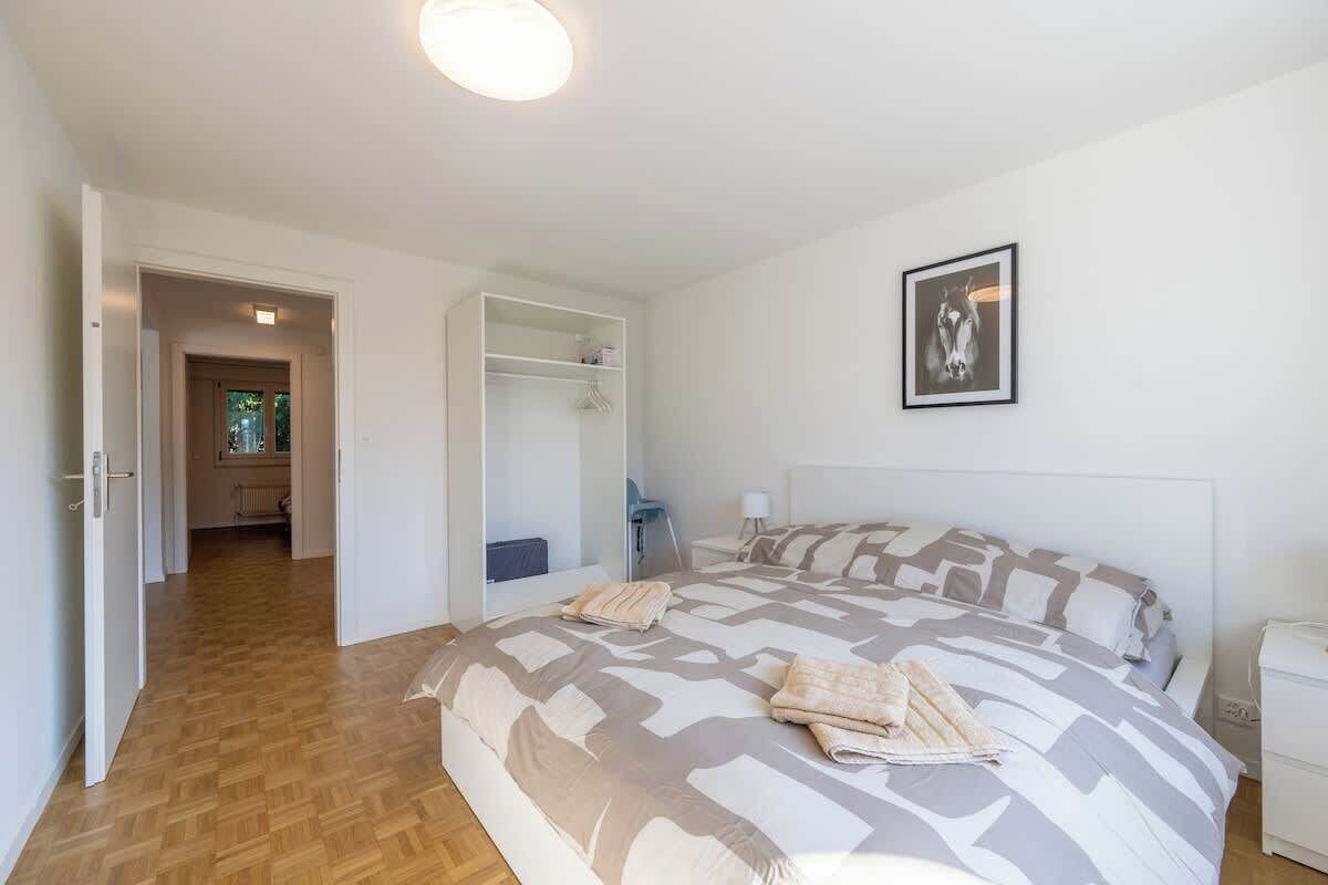 A bedroom with a large bed, a bedside table, a nightstand, a wardrobe, and a framed picture on the wall.