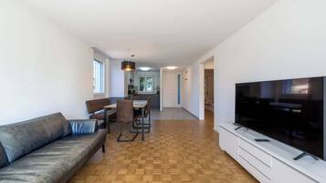 Ein modernes Wohnzimmer mit einer Couch, einem Esstisch, Stühlen und einem Fernseher.