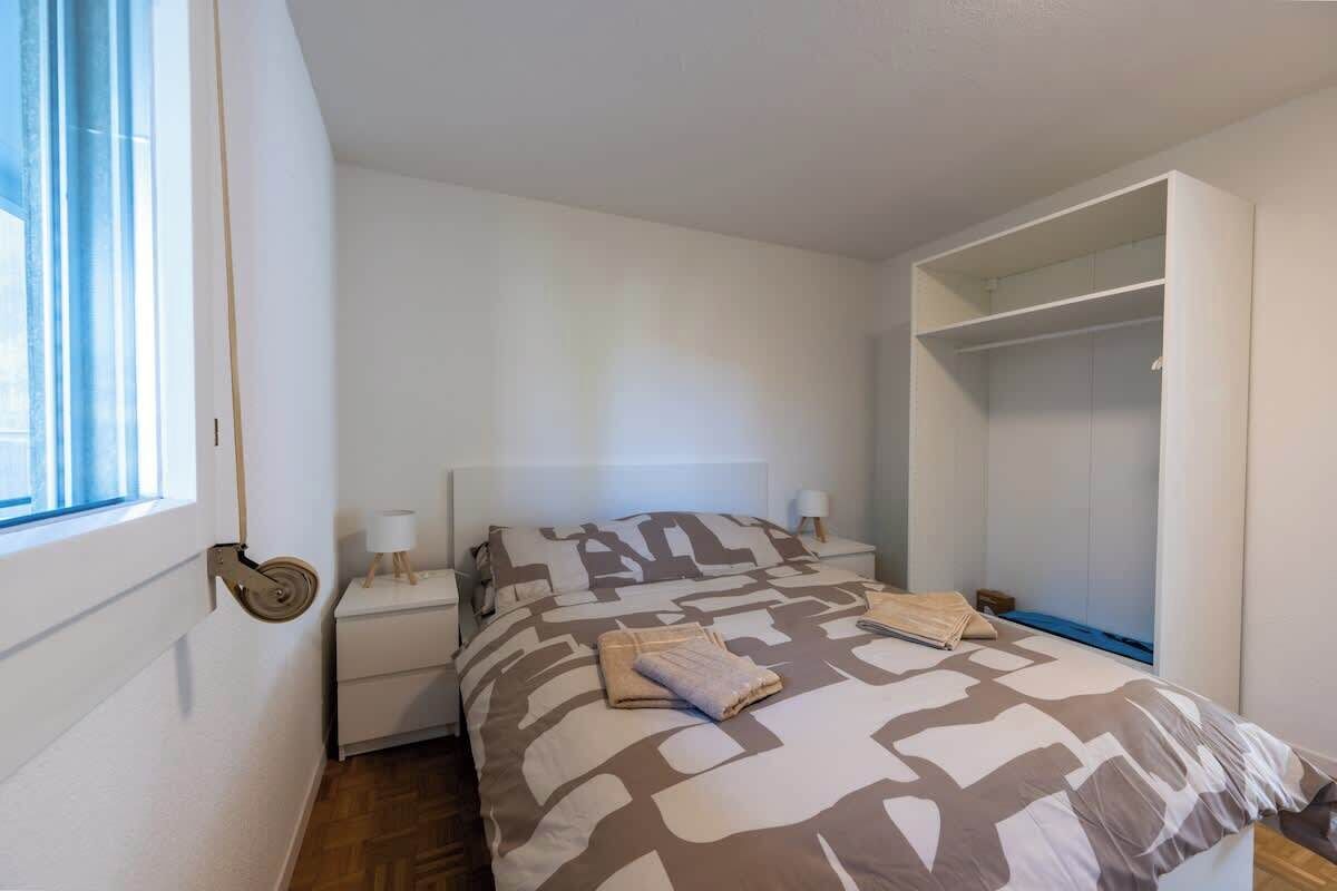 Et soveværelse med seng, to sengeborde, et vindue og en indbygget garderobe.