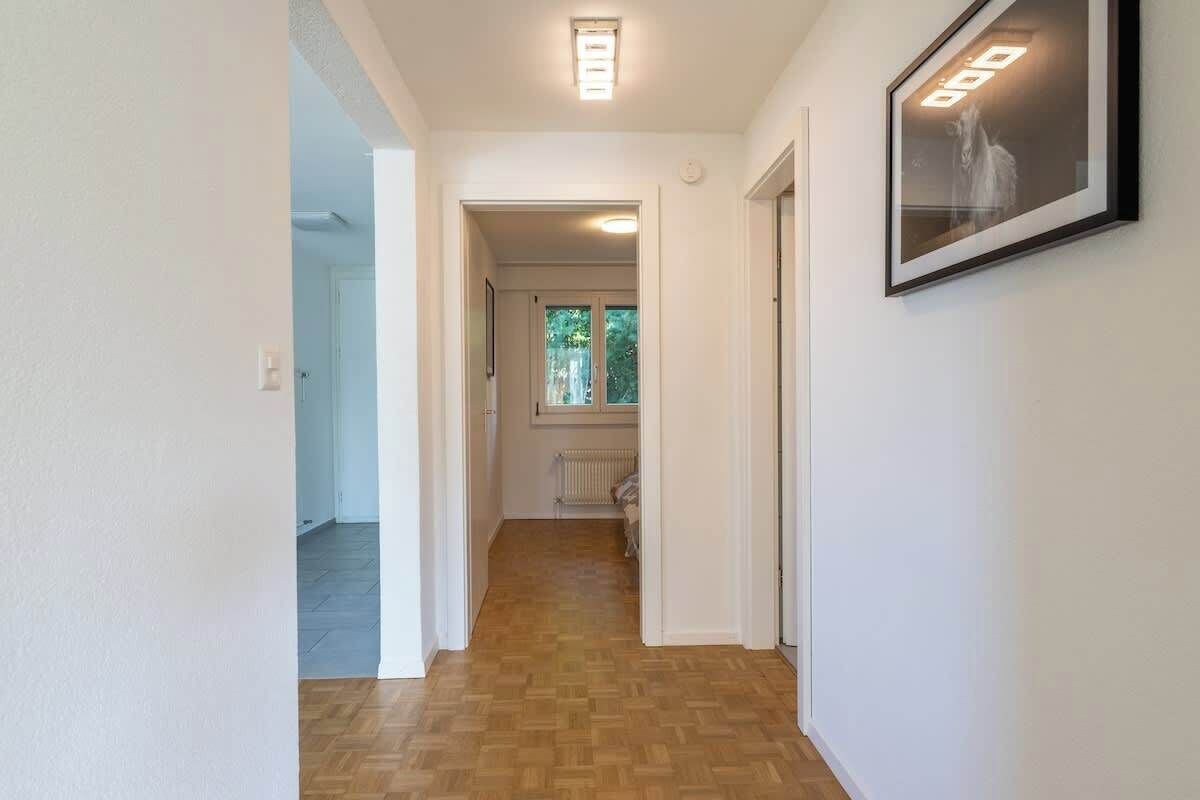 Ein Flur mit Holzboden, weißen Wänden und einem gerahmten Bild auf der rechten Seite.