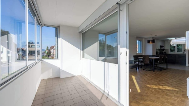 En modern lägenhet med stora skjutbara glasdörrar, ett köksområde och en matplats.