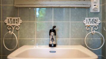 A bathroom with a sink, two towel rings labeled "MR" and "MS," and a faucet.