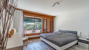 Un dormitorio moderno con una cama grande, un escritorio y vistas a un balcón.