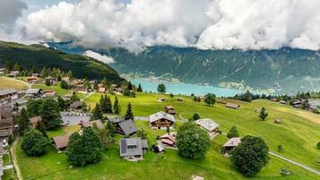 Un village de montagne avec des maisons, un lac et un ciel dégagé.