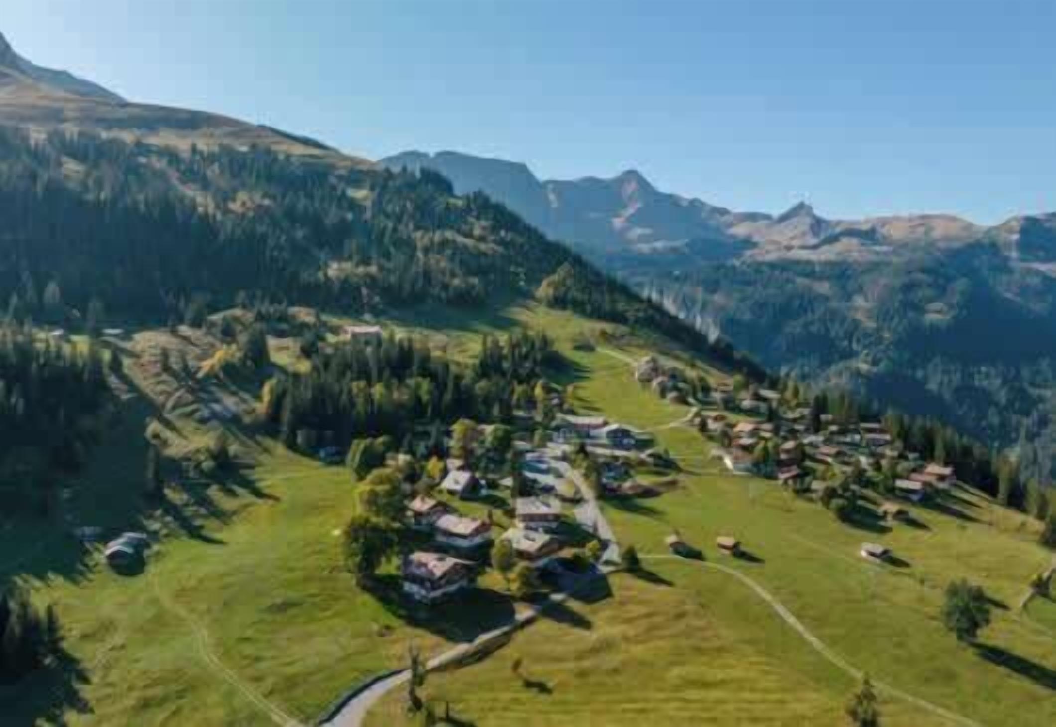 Ein ländliches Dorf mit Häusern, die sich über ein Tal erstrecken, umgeben von Bergen.