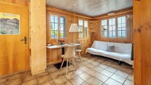 A wooden interior with a dining table, chairs, a sofa, and a window with a view. - Lake and Mountain View Chalet,Fireplace and Garden (Axalp)