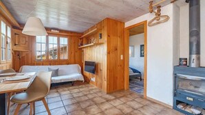 A cozy cabin with a wooden interior, a dining area, a sofa, a TV, and a wood stove. - Lake and Mountain View Chalet,Fireplace and Garden (Axalp)