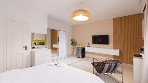 Un dormitorio moderno con una cama grande, un televisor montado en la pared y una lámpara colgante de diseño.