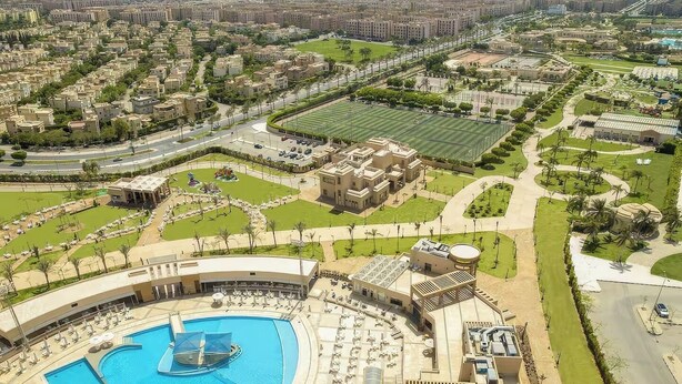 Un extenso complejo hotelero con varias construcciones, una piscina y un campo deportivo.