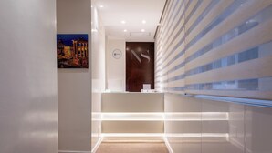A modern reception area with a minimalist design, featuring a reception desk, a framed artwork, and a wall-mounted sign. - Navona to Stay (Rome)