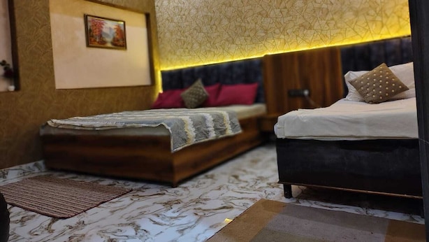A bedroom with a bed, a sofa, a rug, and a wall with a geometric pattern. - Kashiyana Stay (Varanasi)