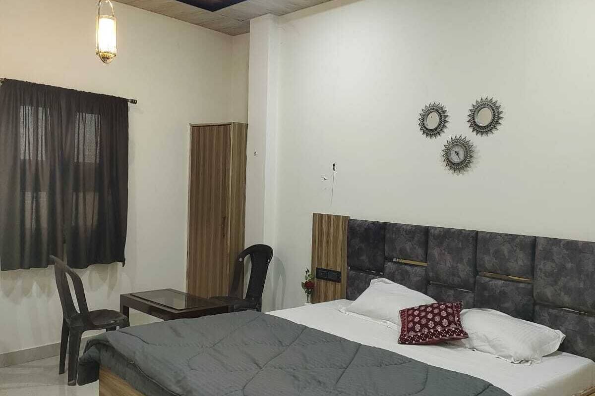 A bedroom with a bed, a desk, a chair, a ceiling fan, and a wall-mounted light fixture.