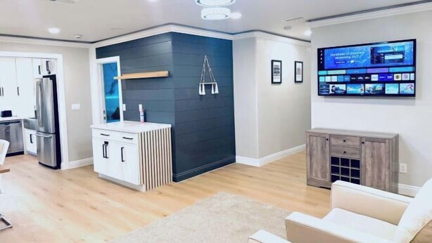 Una sala de estar moderna con un televisor de pantalla plana montado en la pared, una pared de acento oscura y un mueble de madera.