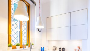 Une cuisine moderne avec un plan de travail blanc, une fenêtre aux montants jaunes et deux tabourets.