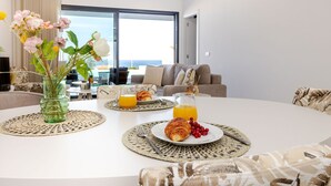 A dining table with a vase of flowers, plates with croissants and berries, and glasses of orange juice. - Vale Furado Sea & Nature - BY SCH (Nazaré)