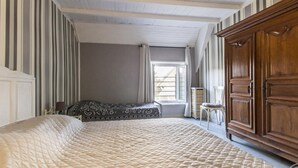 Un dormitori amb un llit gran, un armari de fusta i una finestra amb cortines.