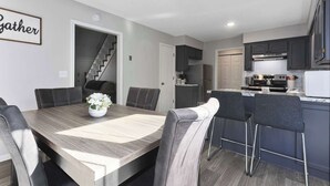 Une cuisine moderne avec des meubles de couleur sombre, une table à manger en bois et un ventilateur de plafond.