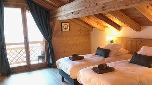 Habitación de cabaña de madera con dos camas, un balcón y un cuadro en la pared.
